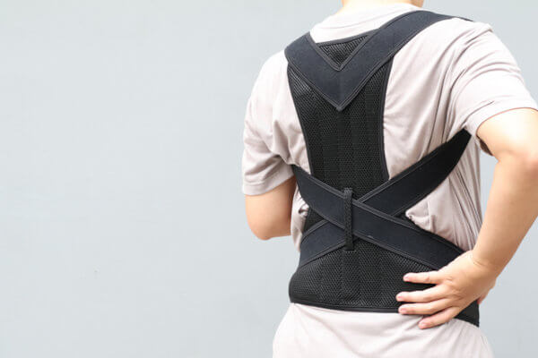 ανδρας φοράει τον κηδεμόνα για τη σκολίωση